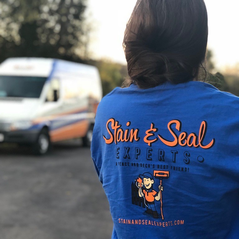 Photo of the back of a woman wearing a Stain and Seal Experts shirt in blue