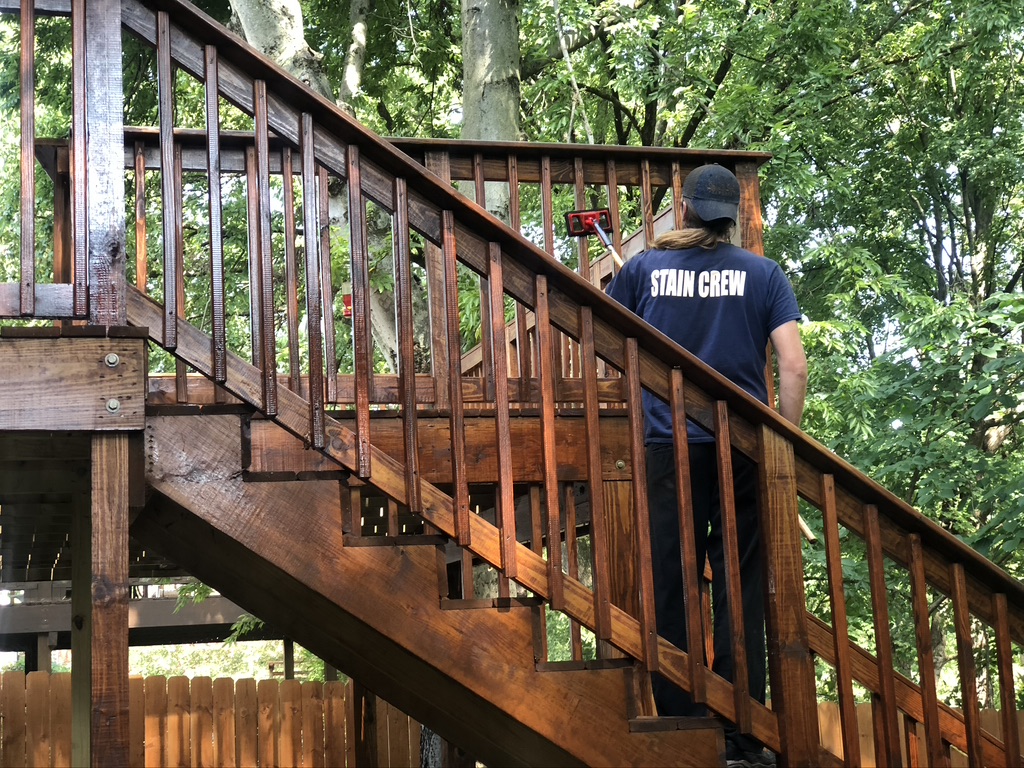 Photo of a wood deck with stair being stained by a professional